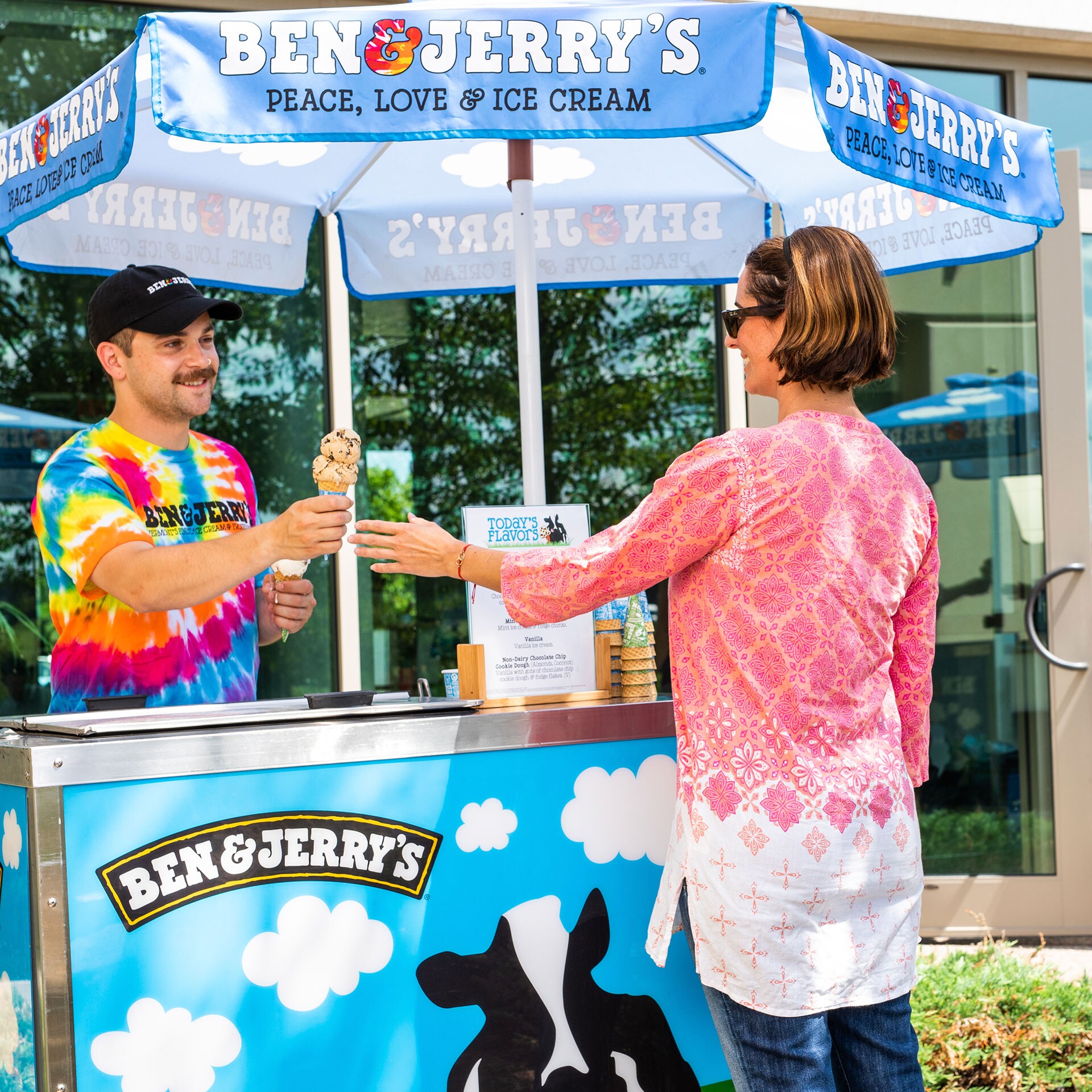 Two people at a catering cart exchanging a ice cream cone